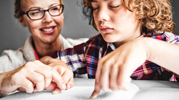 An image of a teacher and student reading braille.